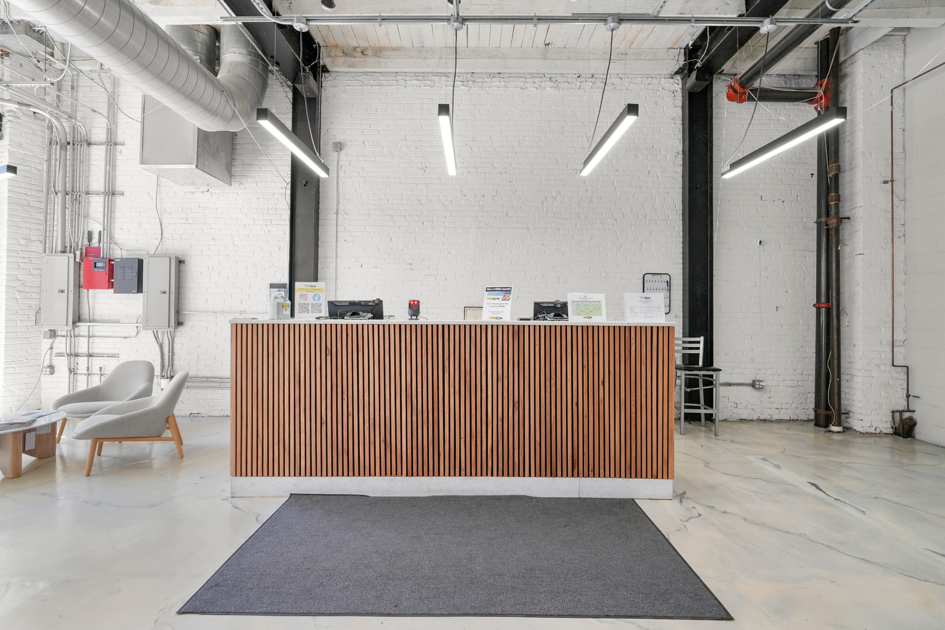Reception desk with wood slat cladding under exposed brick and structure